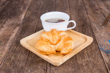 coffee and croissant for breakfast on rustic wooden table