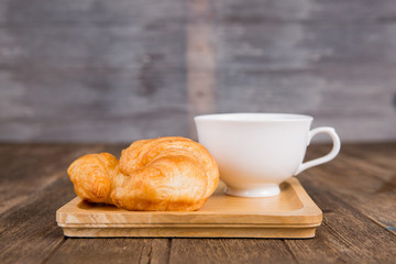 coffee and croissant for breakfast on rustic wooden table