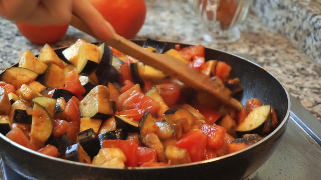 Healthy food lifestyle: beautiful woman casually cooking, stir, simmer vegetable in pan at kitchen. Close-up shot, handheld.