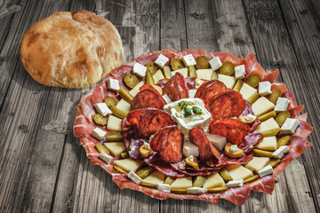 Plateful of Serbian Appetizer Meze with Pita Bread on Old Cracked Floorboards Background