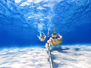 Underwater selfie shot with selfie stick. Couple swimming at the bottom of the sea. Deep blue sea....