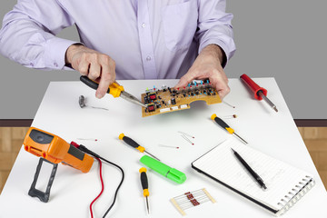 Electronic test engineer using long nose pliers to mount component in a circuit board