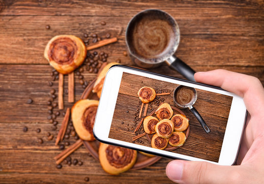 Hands taking photo cinnamon rolls with smartphone. 