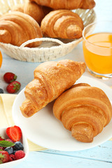 Fresh tasty croissants with berries on blue wooden background