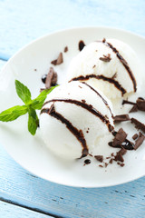 Sweet ice cream in plate on blue wooden background
