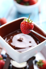 Chocolate fondue with fresh berries on a blue wooden table