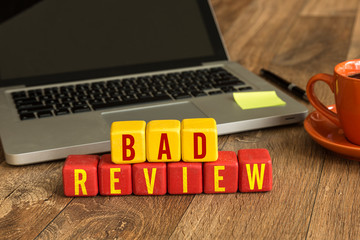 Bad Review written on a wooden cube in a office desk