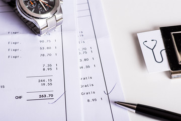 Office desk with an budget planner, a watch, a pen and business cards.