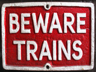 Old vintage red retro distressed railway enamel metal sign with text, beware trains