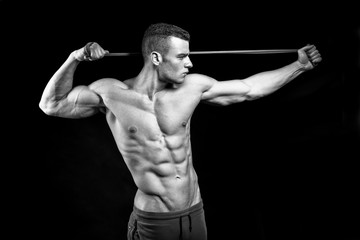 Muscular fitness man presents his body building on black background