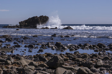 Waves crash against rock formations on a beach in Southern California. 