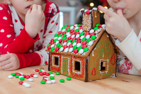 Little adorable girls decorating gingerbread house for Christmas