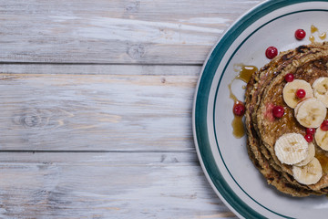 Stack of healthy low carbs oat pancakes over white wooden background