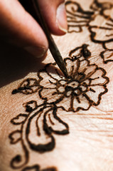 Henna tattoo drawing with herbal dye on foot floral design macro closeup