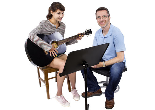 Music teacher tutoring young female student how to play guitar