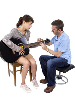 Music teacher tutoring young female student how to play guitar