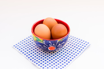 Aerial view brown eggs in colorful ceramic bowl isolated on table