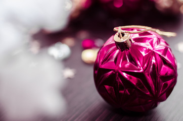 Magenta christmas ball on bokeh background of xmas ornaments. Merry christmas. Winter holidays. Xmas theme. Happy New Year. Blurred background.