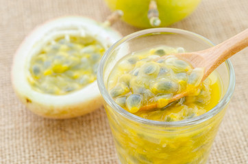 Passion fruit juice in glass with wooden spoon.