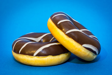 Two chocolate donuts on the blue background