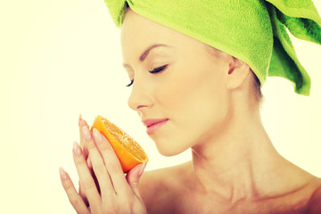 Beautiful woman smelling orange.