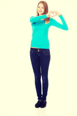 Fototapeta premium Smiling teenage woman making heart shape