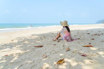Young female sitting and relax on tropical beach looking to sea