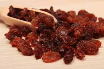 Brown raisins with spoon on wooden table, healthy eating