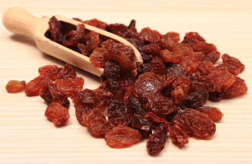 Brown raisins with spoon on wooden table, healthy eating
