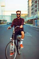 Man in sunglasses riding a bike on city street