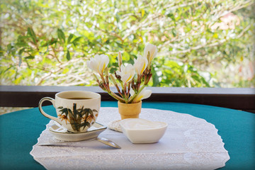 Classic white cup of black coffee decorated with flower and tree background