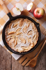 Dutch baby pancake with apples in a pan closeup. vertical top view
