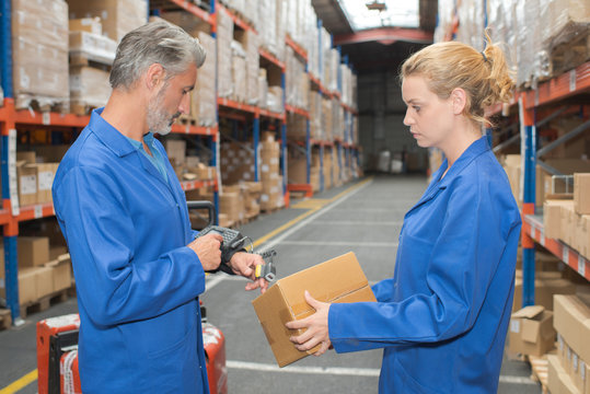 Man and woman in warehouse scanning box with scanner on finger