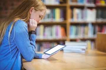 Student with smartwatch using tablet in library