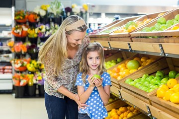 Daughter holding an apple at grocery shop