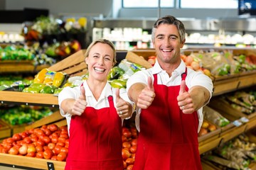 Smiling couple showing thumbs and wearing apron 