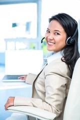 Smiling  businesswoman with headset using laptop 