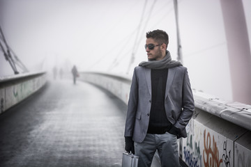 Handsome trendy man walking on a bridge in winter