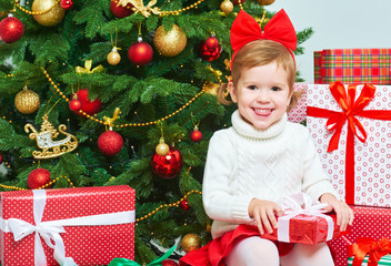 happy child with Christmas gifts near a Christmas tree