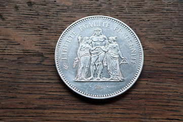 pièce de cinquante francs en argent sur table en bois