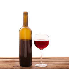 Glass and bottle of red wine unusually on wooden background.