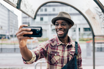 Half length of a young handsome afro black man holding a smartph