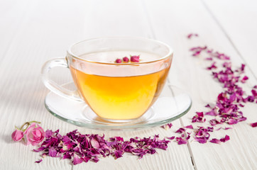 Rose tea and dried petals on white wooden table