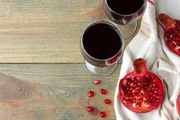 juicy pomegranate on the fabric and the glasses of wine on wooden background