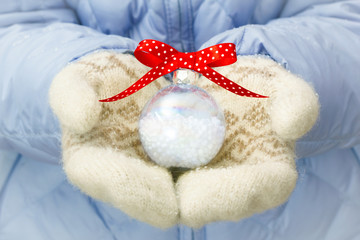 Woman holding christmas ball in her arms outdoor in winter