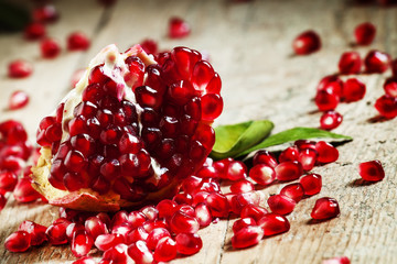 Fresh peeled pomegranates with ruby red beans on old wooden tabl