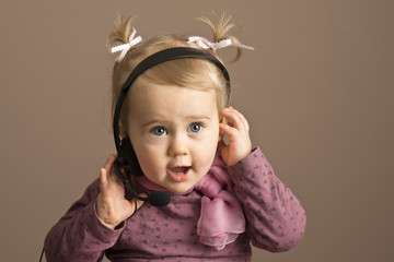 Baby girl talking on a headphones - obrazy, fototapety, plakaty