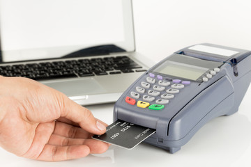 Hand Swiping Credit Card With Laptop In Background