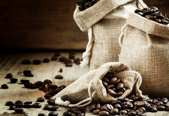 Grains of roasted coffee in bags on old wooden table in rustic s