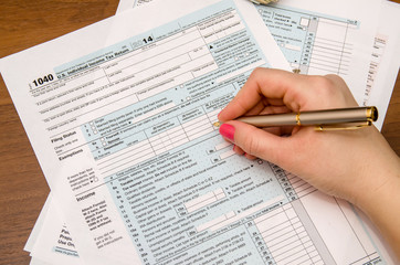 Woman hand filling income tax forms 1040